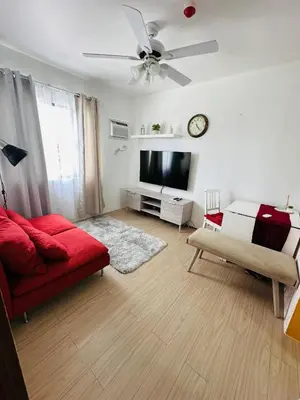 a living room with a red couch and a flat screen tv at Tower C 3rd Floor in Taytay