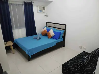 a bedroom with a bed with blue sheets and pillows at Tabatina Grand Reviera Suites in Manila