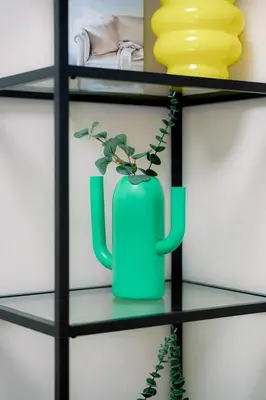 a green vase on a glass shelf with a plant at Cozy 1BR Condo in McKinley West in Manila