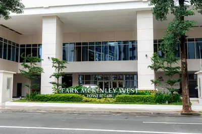a building with a sign in front of it at Cozy 1BR Condo in McKinley West in Manila