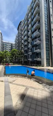 a swimming pool in front of a tall building at Rqui Condotel Rooms Near Airports and Newport World Casino in Manila