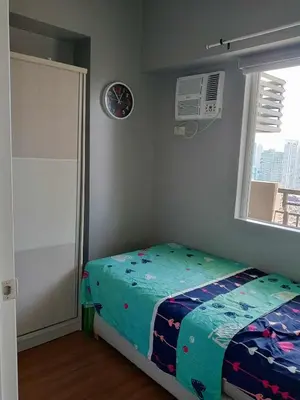 a bedroom with a bed in a room with a window at Sweet Condo in Manila