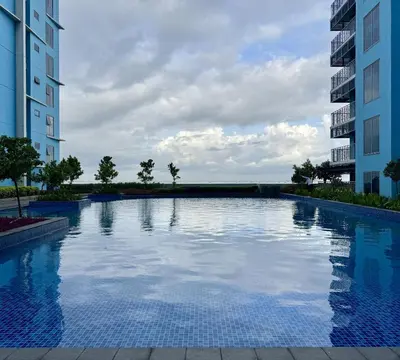 a large swimming pool between two tall buildings at Panoramic Seaview 2BR near Airport Facing the Bay 6G in Manila