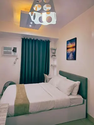 a bedroom with a bed with a green curtain at Modern Cozy Studio in Dasmariñas