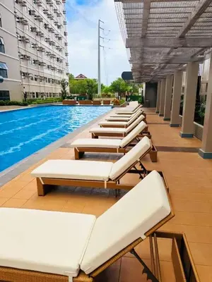 a row of lounge chairs next to a swimming pool at Modern Cozy Studio in Dasmariñas