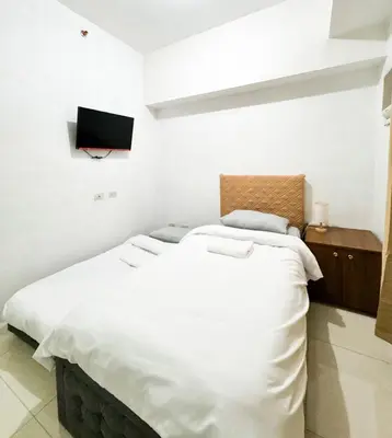 a large white bed in a room with a tv at Convertible Solo Budget Studio in Salcedo Village in Manila