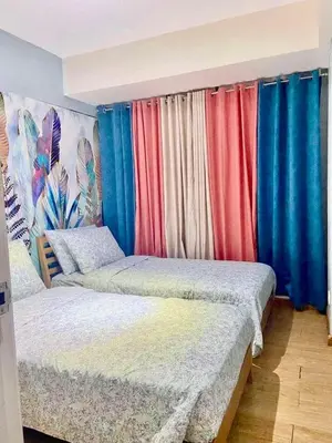 two beds in a room with colorful curtains at Leisure escape Azure staycation in Manila