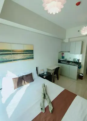 a bedroom with a large white bed with boots on it at The Catalina at The Beacon Makati in Manila