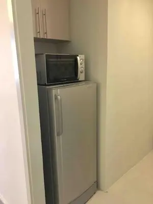a microwave sitting on top of a refrigerator at Rustic 1 BR Apartment Poolside View in Manila