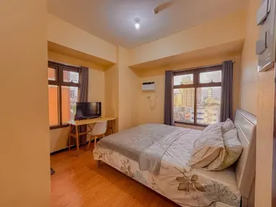 a bedroom with a bed and a desk and two windows at The Radiance Manila bay 2BR in Manila