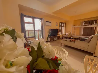 a living room with a couch and a table with flowers at The Radiance Manila bay 2BR in Manila