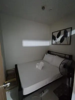 a bedroom with a bed with a pillow and a fan at Aldo Staycation mall of Asia in Manila