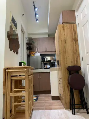 a kitchen with wooden cabinets and a counter with two stools at EK's Place in Manila