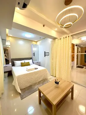 a bedroom with a large bed and a table at HomeSuiteHome, Shore 3 Residences Moa Complex, Pasay City in Manila