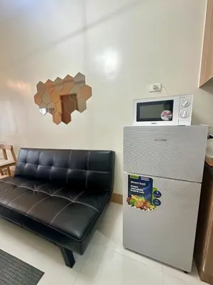 a room with a refrigerator and a black leather couch at Mall of Asia Staycation with fast wifi and google tv in Manila