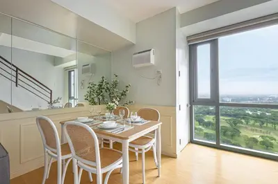 a dining room with a table and chairs and a large window at 2 BR Golf View Loft Timeless Charm in Avant BGC in Manila