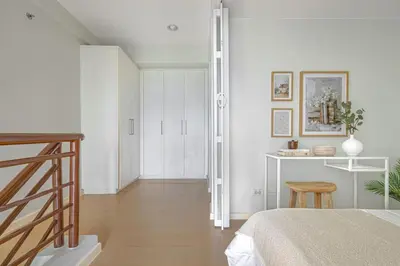 a bedroom with white walls and a bed and wooden floors at 2 BR Golf View Loft Timeless Charm in Avant BGC in Manila