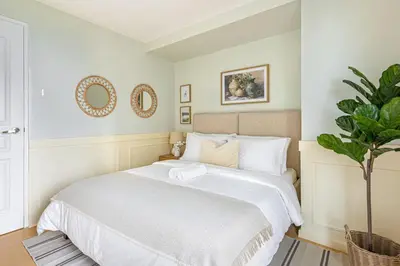 a bedroom with a white bed and a plant at 2 BR Golf View Loft Timeless Charm in Avant BGC in Manila