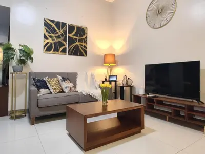 a living room with a couch and a flat screen tv at Uptown BGC Spacious 1BR Unit by Terravista - Prague Suite in Manila