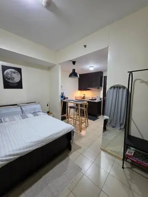 a bedroom with a large bed and a kitchen at Pioneerwoodlands Mandaluyong Studio Unit in Manila