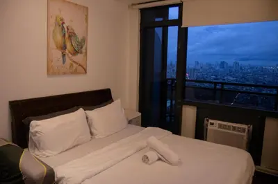 a bed in a room with a large window at D-Studio,Best Sunset Pool,Luxury,Hotel Style in Manila