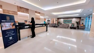 a woman standing at a counter in a hotel lobby at Chateau Staycation in Manila