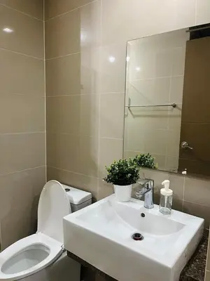 a bathroom with a sink and a toilet and a mirror at Kyedenz Unit -Two Palm Tree Villas Newport Naia T3 in Manila