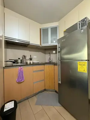 a kitchen with a stainless steel refrigerator and wooden cabinets at Lovely Condo Across NAIA T3 Newport with WiFi in Manila
