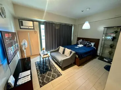 a bedroom with a bed and a couch and a tv at Studio Unit Across NAIA T3 Airport MNL in Manila