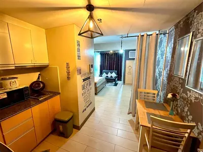 a kitchen with a table and a ceiling at Homey Studio at Two Palm Tree Across NAIA T3 Airport in Manila