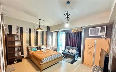 a bedroom with a bed and a chair in it at Homey Studio at Two Palm Tree Across NAIA T3 Airport in Manila