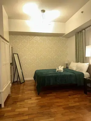 a bedroom with a bed with a green blanket at Spacious Studio in Mosaic Tower no Balcony in Manila