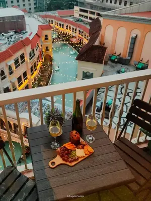 a table with a plate of food and two glasses of wine at One Bedroom Unit with Venice Canal View in Manila