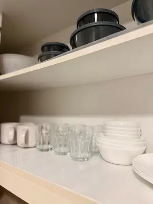 a shelf with dishes and glasses on it at Cozy & Stylist Unit in BGC in Manila