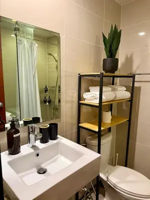 a bathroom with a sink and a toilet and a mirror at Netflix and Chill Cozy Unit BGC in Manila