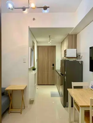 a kitchen with a refrigerator and a table in it at Fame Residences One-Bedroom Condo Unit in Manila