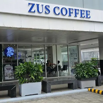 a zus coffee shop with two potted plants in front of it at MOA Shell Residences Spacious 1BR with City View WiFi and Netflix in Manila
