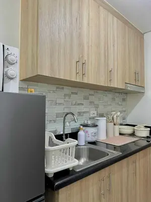 a kitchen counter with a sink and a refrigerator at Aurbana Staycation in Manila