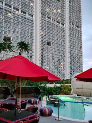 a swimming pool with red umbrellas and chairs and a swimming pool at Acqua at The Hotel Residences Acqua Manila near Makati and BGC in Manila