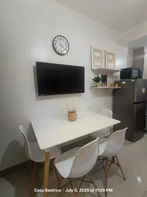 a dining room table with chairs and a clock on the wall at Cozy 19 at Shore 2 Residences in Manila