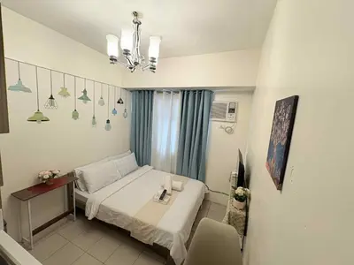 a bedroom with a bed and a table and a chandelier at JJMC HOMESTAY 29 with Netflix and Wifi in Manila