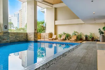 a hotel swimming pool with chairs and a building at Coastal Studio in KL Tower Serviced Residences, Greenbelt, Makati! Maximum capacity 5 pax! in Manila