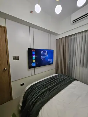 a bedroom with a bed and a tv on the wall at Luxury apartment at Bloom Residences in Manila