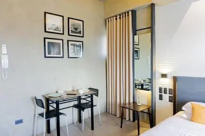 a hotel room with a table and a bed and a bedroom at Spacious Condo with 50in TV & Netflix, Near Malls in Manila