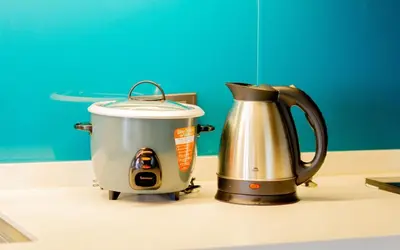 a slow cooker and a tea kettle on a counter at Spacious Condo with 50in TV & Netflix, Near Malls in Manila