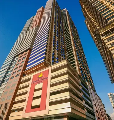 a tall building with a sign in front of it at Grand Riviera Condotel Near St lukes Medical Center in Manila