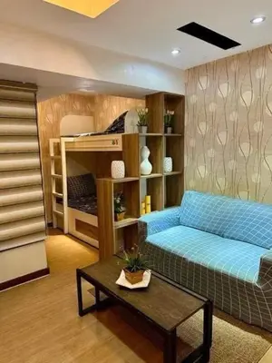 a living room with a blue couch and a bed at Staycation at Starmall in Manila