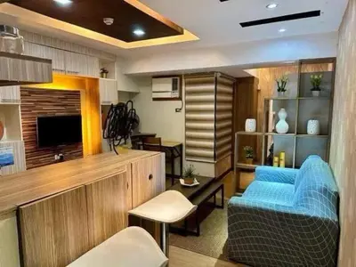 a living room with a blue couch and a television at Staycation at Starmall in Manila