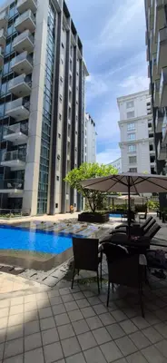a table with an umbrella and chairs next to some buildings at Condotel in Pasay City Manila in Manila