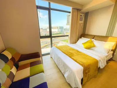 a bedroom with a bed and a large window at Modern 1BR Stay near Solaire, Okada, near Airport in Manila